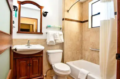 a bathroom with a toilet and a sink and a tub at Brand Plaza Hotel in Glendale