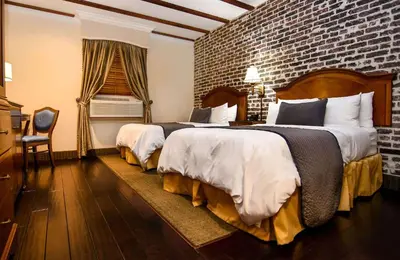 a hotel room with two beds and a brick wall at Brand Plaza Hotel in Glendale