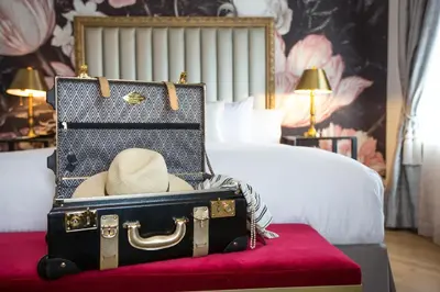a suitcase with a hat sitting on top of a bed at The Culver Hotel in Los Angeles