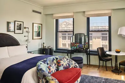 a hotel room with a bed and a chair and windows at Hotel Per La, Autograph Collection in Los Angeles