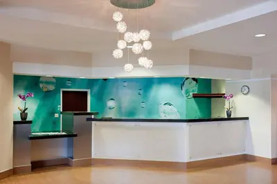 a lobby with a green wall with chandeliers at SpringHill Suites Los Angeles LAX/Manhattan Beach in Hawthorne