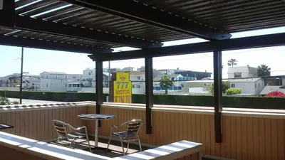 a patio with chairs and a table and a sign at 777 Motor Inn in Huntington Beach