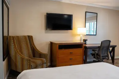 a hotel room with a bed and a desk and a television at The Buena Park Hotel & Suites in Buena Park