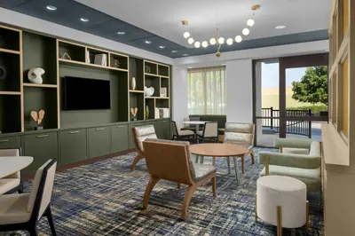 a waiting room with tables and chairs and a tv at Residence Inn Los Angeles Burbank/Downtown in Burbank