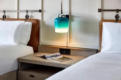 a room with two beds and a table with a magazine at Westdrift Manhattan Beach, Autograph Collection in Manhattan Beach