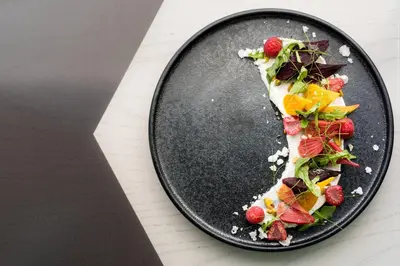 a plate with a piece of pizza with fruit on it at Westdrift Manhattan Beach, Autograph Collection in Manhattan Beach