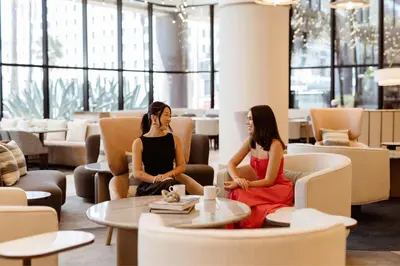 two women sitting in chairs in a lobby at Marriott Long Beach Downtown in Long Beach