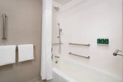 a bathroom with a tub and a shower with towels at Courtyard by Marriott Bakersfield in Bakersfield