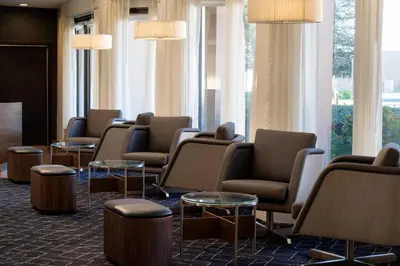 a waiting room with chairs and tables and windows at Courtyard by Marriott Bakersfield in Bakersfield