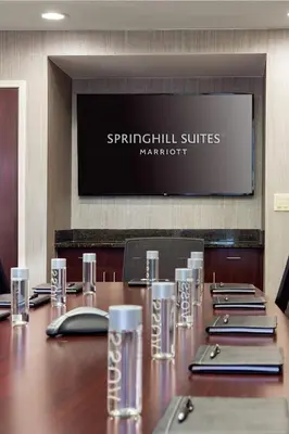 a conference room with a large wooden table with glasses at SpringHill Suites Bakersfield in Bakersfield