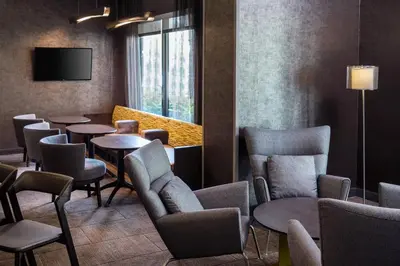 a waiting room with tables and chairs and a tv at SpringHill Suites Bakersfield in Bakersfield