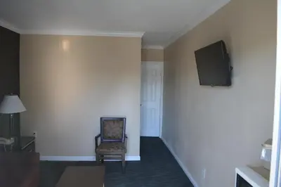 a room with a chair and a tv on a wall at Seaside Motel in Redondo Beach