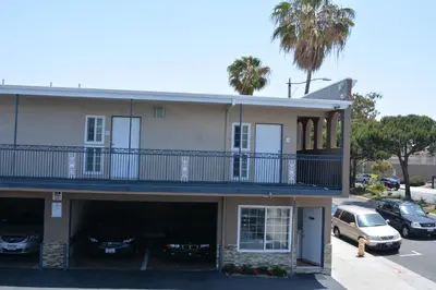 a building with a balcony and cars parked in a parking lot at Seaside Motel in Redondo Beach