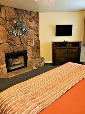a bedroom with a stone fireplace and a television at Snow Lake Lodge in Big Bear Lake
