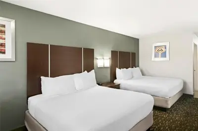 two beds in a hotel room with white sheets at Best Western Desert Villa Inn in Barstow