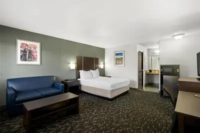 a hotel room with a bed and a blue couch at Best Western Desert Villa Inn in Barstow