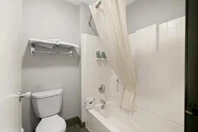 a bathroom with a toilet and a tub and a sink at Best Western Desert Villa Inn in Barstow