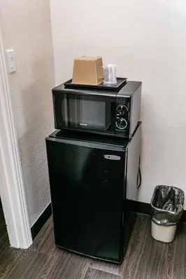 a microwave sitting on top of a black refrigerator at Anaheim Discovery Inn and Suites in Anaheim