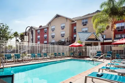 a pool at a hotel with chairs and umbrellas at TownePlace Suites Los Angeles LAX Manhattan Beach in Hawthorne