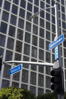 two blue street signs on a traffic light with a building at Libra Hotel in Los Angeles