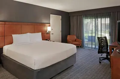 a hotel room with a large bed and a chair at Courtyard Anaheim Buena Park in Buena Park