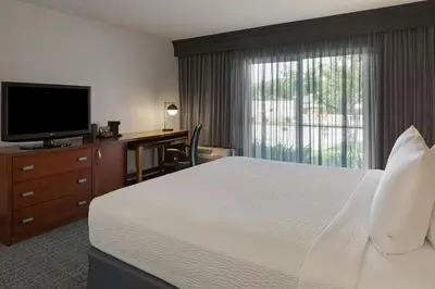 a hotel room with a bed and a desk and a television at Courtyard Anaheim Buena Park in Buena Park