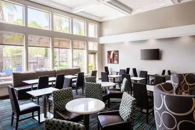 a restaurant with tables and chairs and windows at Residence Inn by Marriott Cypress Los Alamitos in Los Alamitos