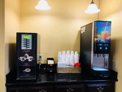 a counter with a coffee maker and a refrigerator at Dynasty Suites Hotel in Riverside
