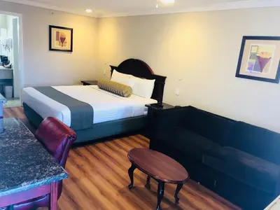 a hotel room with a bed and a couch at Dynasty Suites Hotel in Riverside