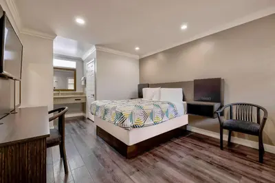 a bedroom with a bed with a desk and two chairs at Motel 6 South Gate CA in South Gate