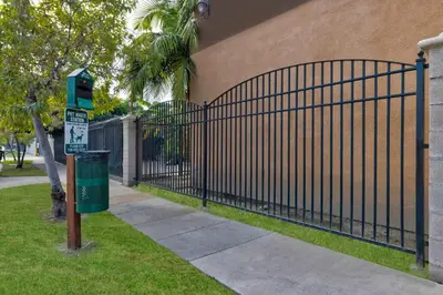 a black iron fence next to a building with a trash can at Motel 6 South Gate CA in South Gate