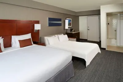 two beds in a hotel room with white sheets at Courtyard by Marriott Los Angeles LAX / Century Boulevard in Los Angeles