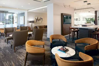 a lobby with chairs and tables and a bar at Courtyard by Marriott Los Angeles LAX / Century Boulevard in Los Angeles