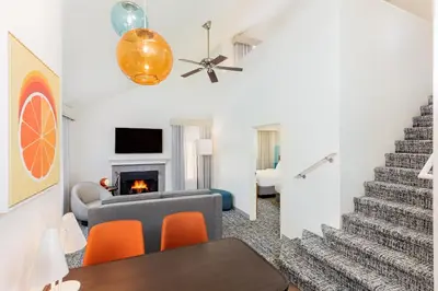 a living room with a staircase and orange chairs at Clementine Hotel & Suites Anaheim in Anaheim