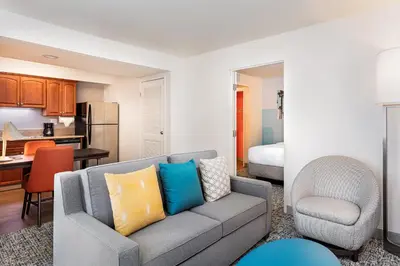 a living room with a couch and a kitchen at Clementine Hotel & Suites Anaheim in Anaheim