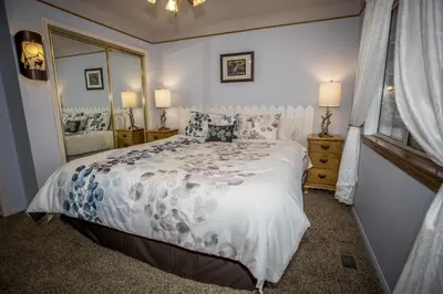 a bedroom with a bed with a white comforter and a mirror at Majestic Pines Home in Big Bear Lake