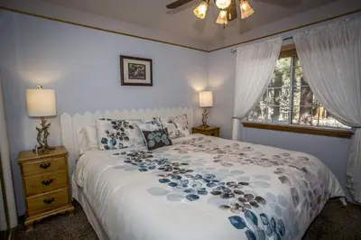 a bedroom with a white bed with blue flowers on it at Majestic Pines Home in Big Bear Lake