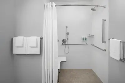 a bathroom with a shower with white towels at Courtyard by Marriott Santa Clarita Valencia in Valencia
