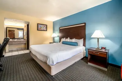 a hotel room with a large bed and a mirror at Glenridge Inn Glendale - Pasadena in Glendale