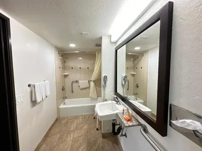a bathroom with a sink and a tub and a mirror at Glenridge Inn Glendale - Pasadena in Glendale