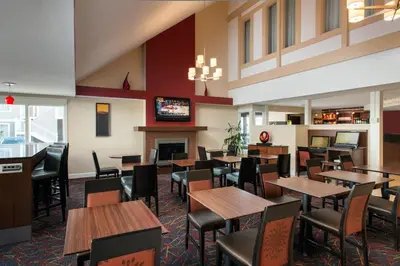 a restaurant with tables and chairs and a fireplace at Residence Inn by Marriott Long Beach in Long Beach