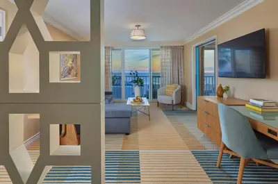 a living room with a couch and a desk with a television at Viceroy Santa Monica in Los Angeles