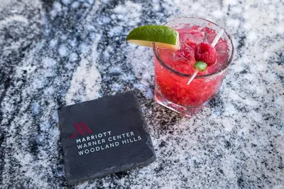 a drink with a raspberry and lime on a table at Warner Center Marriott Woodland Hills in Woodland Hills