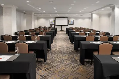 a conference room with tables and chairs and a screen at Warner Center Marriott Woodland Hills in Woodland Hills