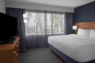 a hotel room with a bed and a flat screen tv at Courtyard by Marriott Cypress Anaheim / Orange County in Cypress