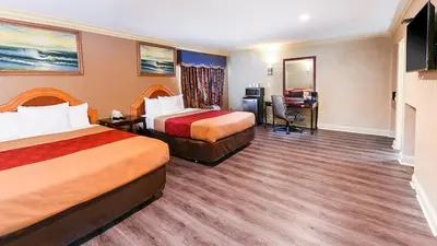 a hotel room with two beds and a desk at Pacifica Motel in Long Beach