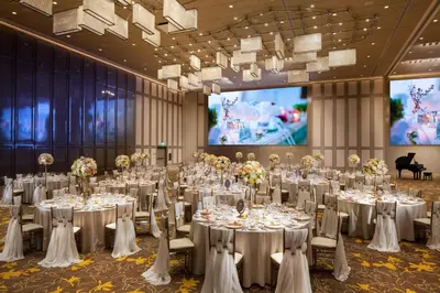 a banquet hall with white tables and chairs and a screen at Sheraton Los Angeles San Gabriel in San Gabriel
