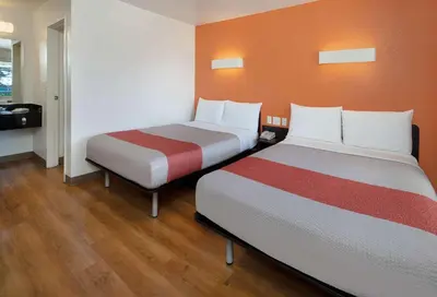 a room with two beds and an orange wall at Motel 6-Arcadia, CA - Los Angeles - Pasadena Area in Arcadia