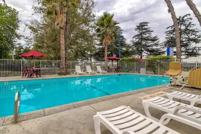 a swimming pool with chairs and tables and trees at Motel 6-Arcadia, CA - Los Angeles - Pasadena Area in Arcadia
