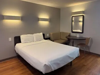 a bedroom with a large white bed and a table at Motel 6-Simi Valley, CA in Simi Valley